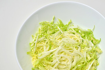 Chinese cabbage salad in white bowl over white. Vegan food lifestyle concept.
