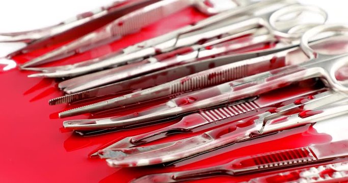 Dolly out close up of surgical instrument tools with blood, scalpel forceps tweezers, scissors for surgeon in surgery
