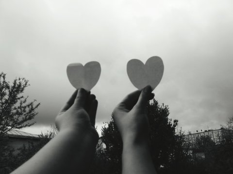 Close-up Of Hands Holding Heart Against Clouds