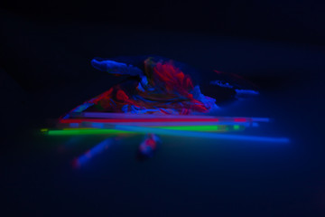 Hand in ultra violet light with neon sticks and colors