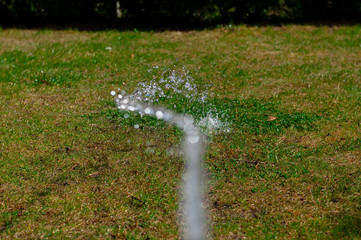 A stream of water irrigates a green lawn
