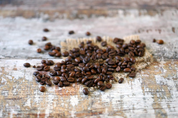 Selective focus. Macro. Coffee beans are scattered on a wooden surface.