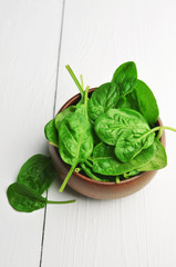 Fresh spinach leaves in wooden bowl over white wooden table. Healthy vegan food. Green living and...