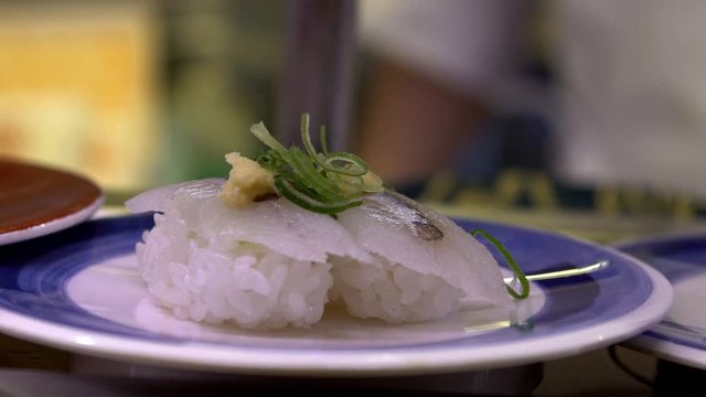 Slow motion of sushi on moving conveyor belt in a Japan restaurant. Traditional Kaitenzushi Japanese food. Shushi Go Round is a famous form of fast food common in Asia, also known as sushi train.-Dan