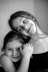 Fototapeta premium Black and white portrait of two little systerichka girls hugging each other and laughing joyfully. Family values. Friendship. Joy