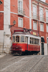 Fototapeta na wymiar Lisbon, Portugal. Vintage red retro tram on street tramline in Alfama district of old town. Popular touristic attraction