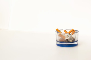Glass ashtray with faded cigarette butts on an isolated white background. Healthy breathing
