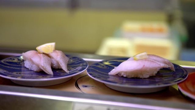 4K, Sushi on moving conveyor belt in a Japan restaurant. Traditional Kaitenzushi Japanese food. Shushi Go Round is a famous form of fast food common in Asia, also known as sushi train.-Dan