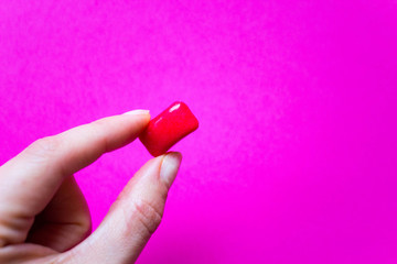 Hand holding Red chewing gum top view on a pink background. Concept of hygiene and clean teeth.  Free copy space.