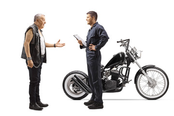 Motorcycle mechanic talking with a mature biker with chopper