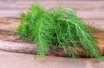 Bunch of fresh green dill on the wooden background closeup. Aromatic condiment dill for cooking.