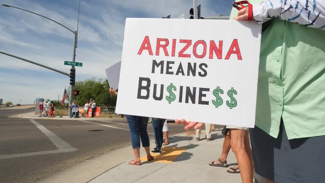 A woman holding a sign reading Arizona Means Business