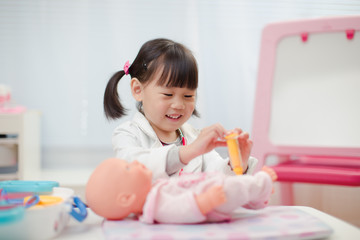 Fototapeta premium toddler girl pretend play doctor role at home against white background