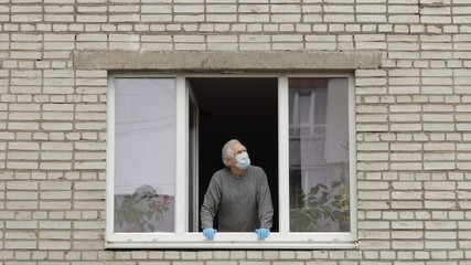 Old man grandfather stay at window isolated at home on quarantine. Coronavirus