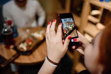 beautiful female photographs her food on cellphone. foodblogger