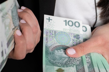 The woman is counting exactly one hundred zlotys paper banknotes.