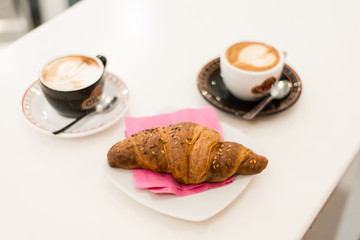 fresh baked croissant with coffee on white table