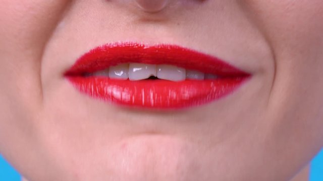 Young girl with bright red shiny lipstick on her sexy lips pronounces the phrases I LOVE YOU, FUCK YOU, I LOVE APPLE, close up.