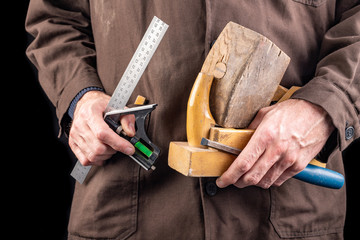 A carpenter with a planer and a hammer in his hand. Worker in a carpentry workshop with tools.