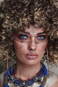 Close-up portrait of young beautiful woman with afro hair and fancy ethnic makeup