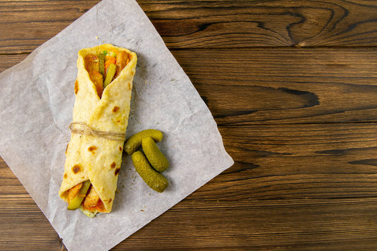 Delicious Turkish Doner Kebab On Pita Bread With Shaved Roasted Meat Off A Traditional Vertical Rotisserie Served With Fresh Salad Ingredients On Rustic Paper, Stand On Wooden Table