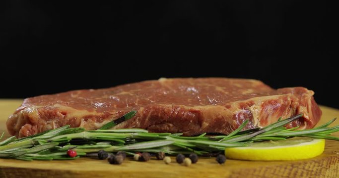 Beautiful meat for steak spinning on black background. Fresh beef displayed on a board decorated with greenery. 5 shots.