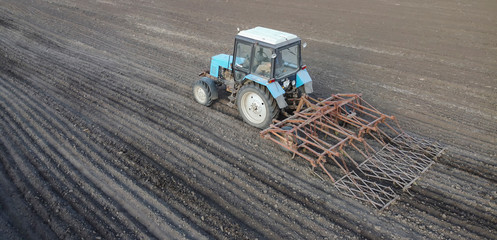 A farmer with a tractor with a cultivator prepares the land for sowing, farming and tillage.
