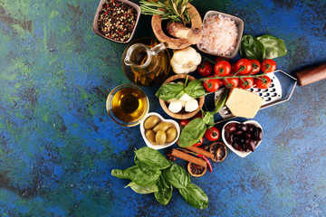 Italian food background with herbs and spices, vine tomatoes, basil, spaghetti, olives, parmesan, olive oil, garlic, peppercorns and fresh rosemary