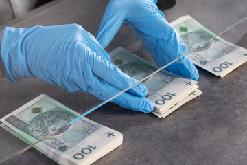Hands of young cashier in protective gloves hand over bundles of banknotes.