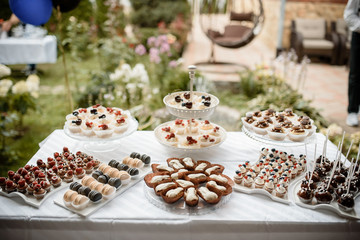 Many cupcakes decorated with cream and berries on a plate