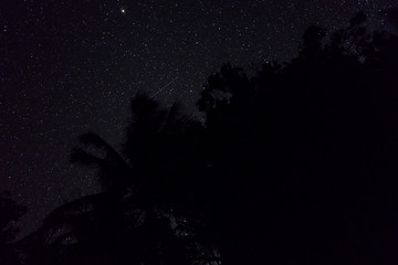 Two falling stars cross each other in nigh sky over the jungle in Banda islands, Maluku, eastern Indonesia