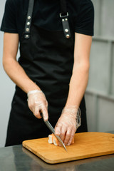 Chef in black preparing sushi Japanese traditional. Man hands making sushi rolls. Close up view. Space for text