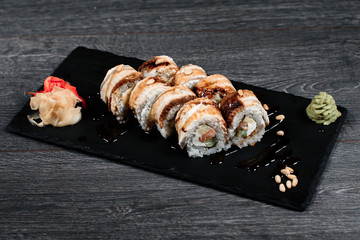 delicious sushi roll set on black plate in restaurant on gray table background