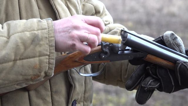 Man discharges a gun pulls out shell ammo unto a shotgun with a sound and smoke