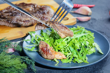 Beautifully laid out freshly cooked steak on arugula. Beef medium rare