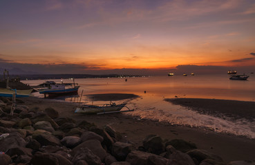 Sumbawa Besar town harbour scene in the evening glassy water long exposure many boats vivid colorful sunset