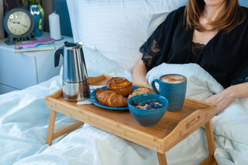 Tray with breakfast food on the bed inside a bedroom. Good morning concept
