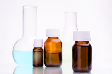 Medicine bottle and laboratory flasks against white background.