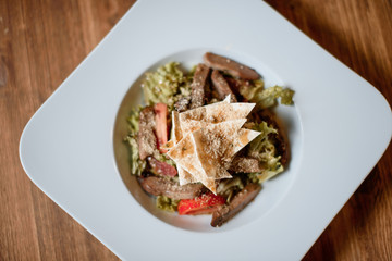 grilled meat with fresh salad on grey served table. traditional dish menu served in a restaurant