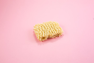 A pile of farfalle pasta in a small white bowl on a pink background