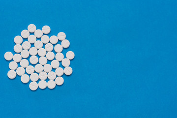 White round tablets on a blue background. Macro of white capsules on blue background.