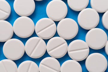 White round tablets on a blue background. Macro of white capsules on blue background.