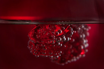 Pieces of red ice plastered with air bubbles in the liquid on a red background. Macro mode. Backgrounds, textures