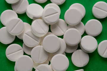 white pills scattered on a green background.