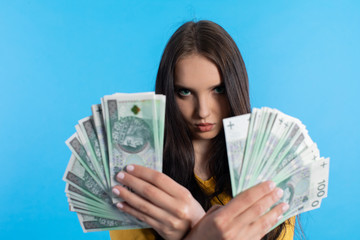 The young woman holds a fan of paper banknotes with a face value of one hundred zlotys.