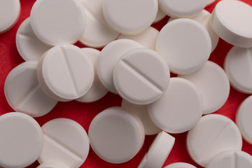 White tablets scattered on a red background