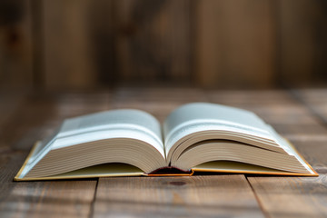A thick book with open hardcover on a wooden floor