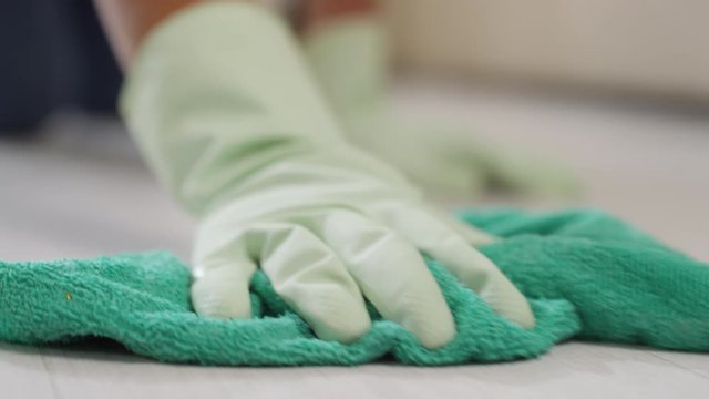 Close up of unrecognizable woman in gloves scrubbing floor with microfiber cloth