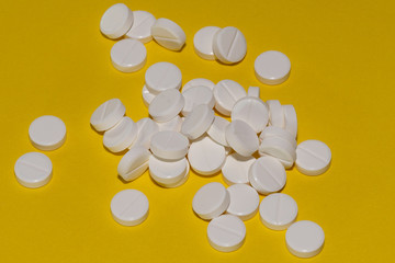 White tablets scattered on a yellow background