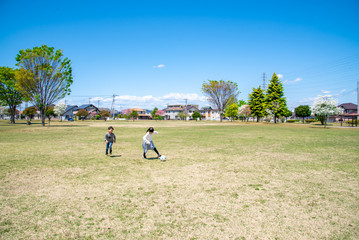 青空の公園でサッカーをする子供